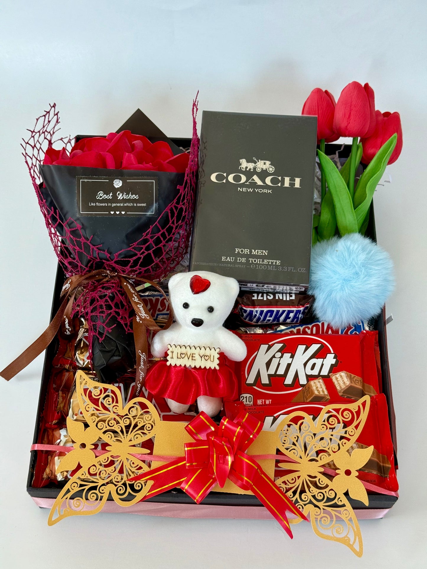 Gift basket with teddy bear, KitKat bars, and Coach perfume on a white background