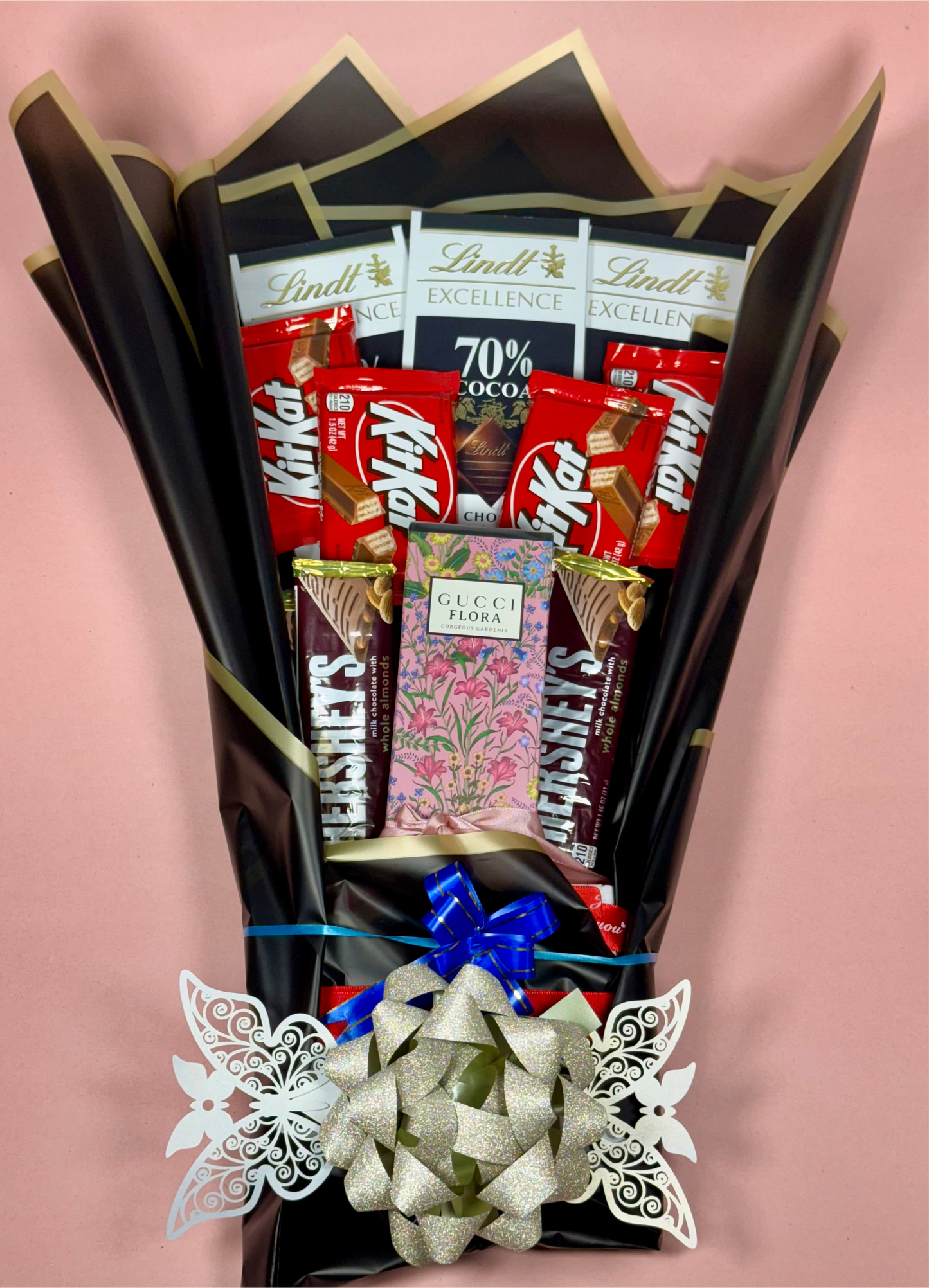 Bouquet of chocolate bars including KitKat, Lindt, and Hershey's on a pink background