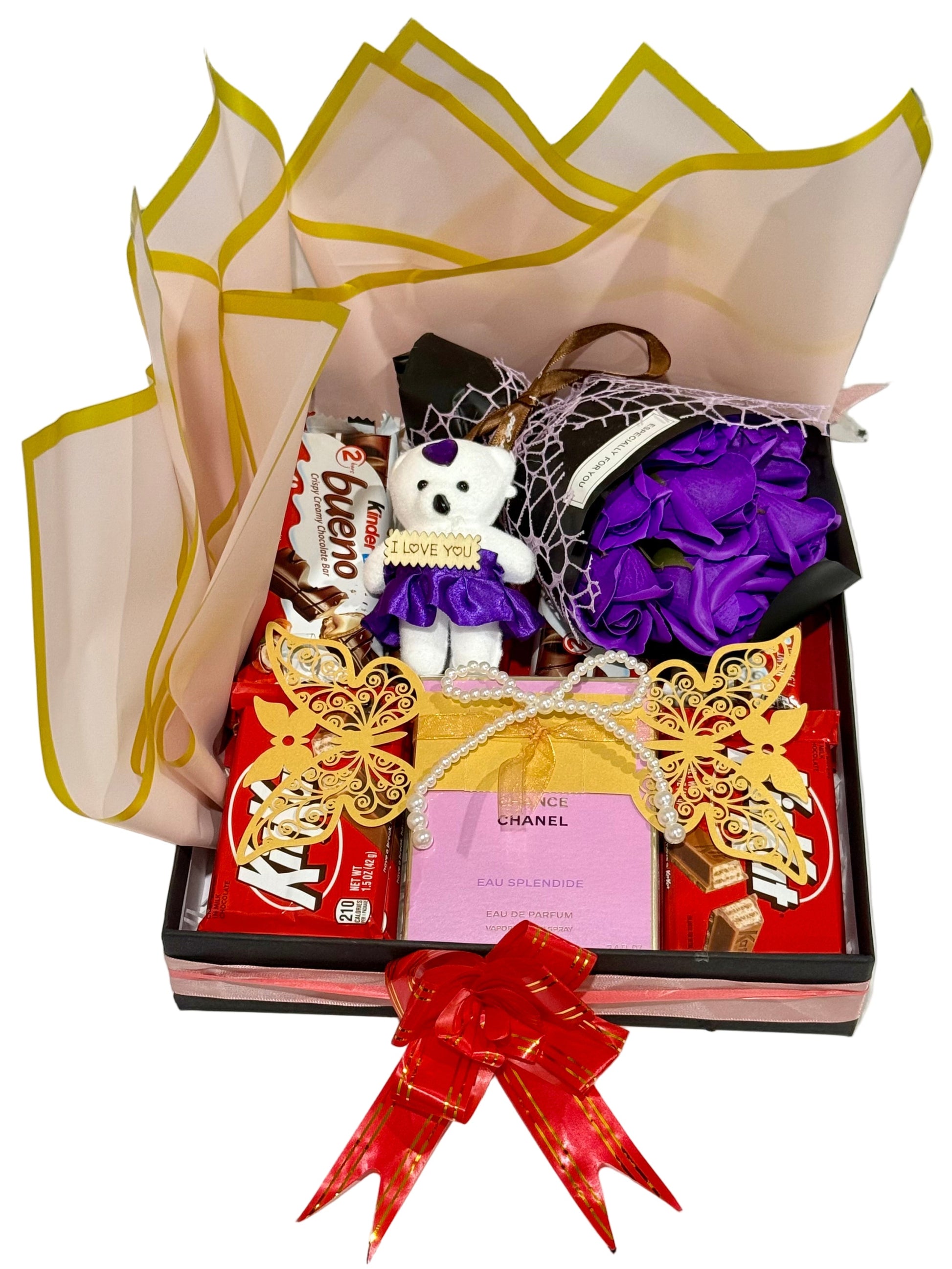 Gift box with a teddy bear, candies, and decorative items on a white surface.