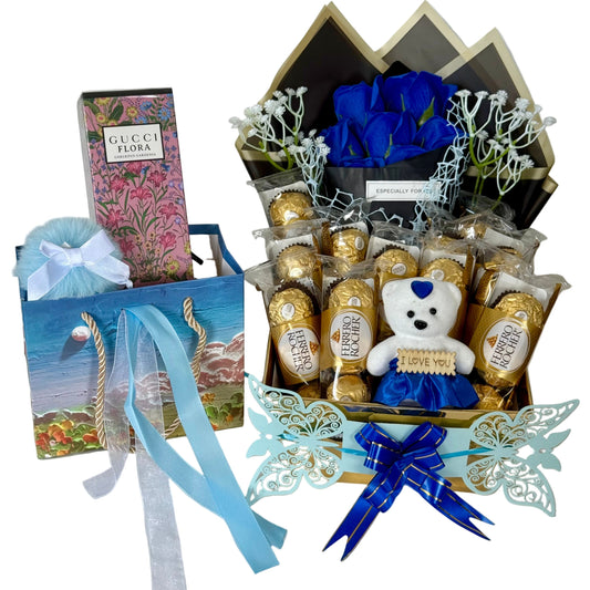 Gourmet gift basket with chocolates, a teddy bear, and flowers on a white background