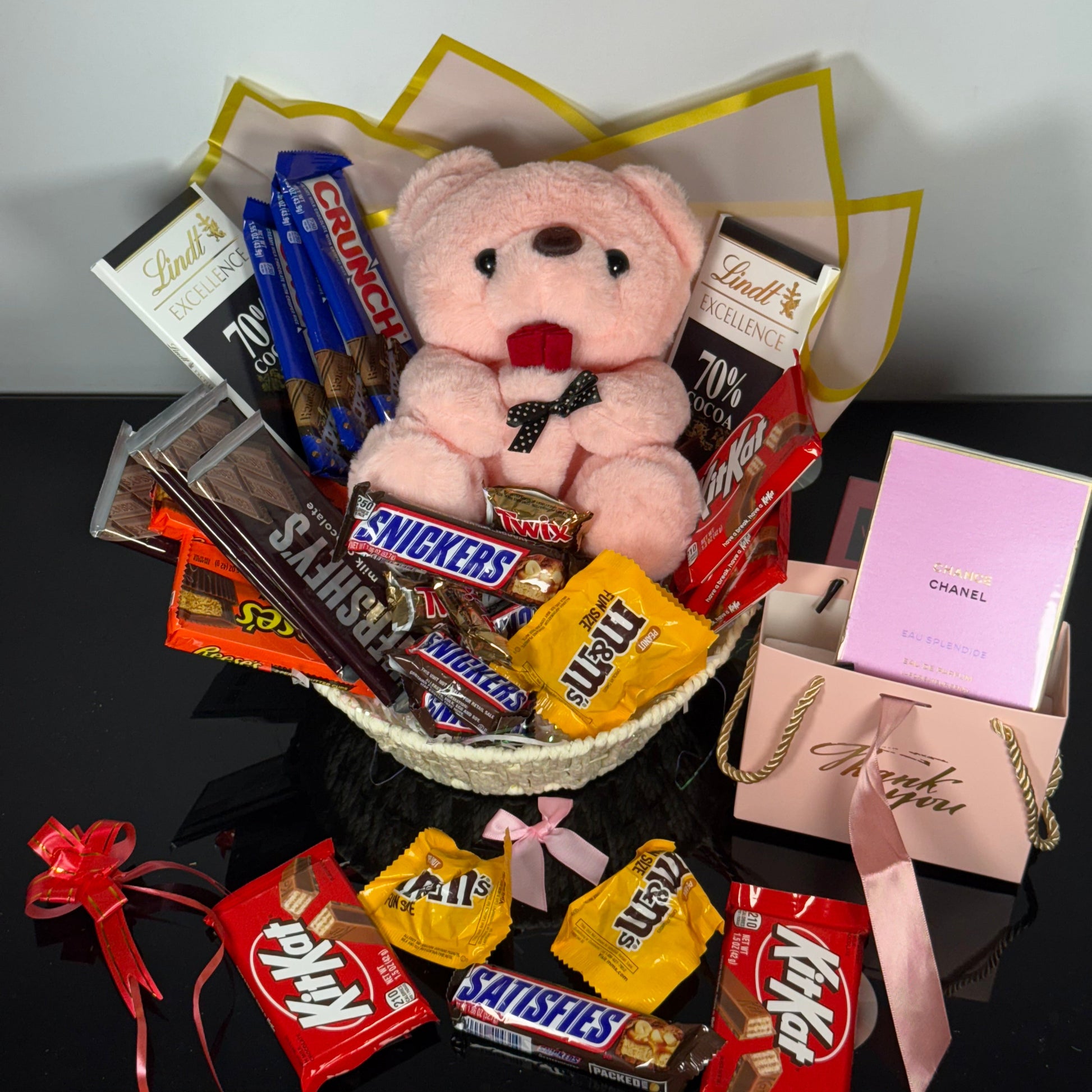 Bouquet of candy bars and a teddy bear arranged in a decorative manner on a white surface.