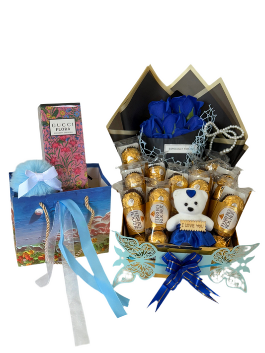 Gift basket with blue roses, teddy bear, and chocolates on a white background