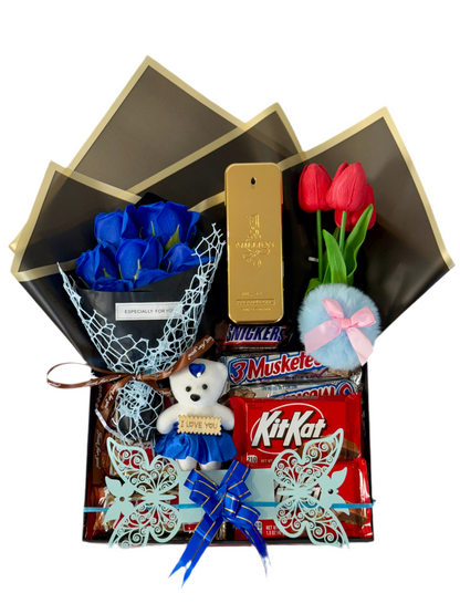Gift set with blue roses, teddy bear, and candy bars in an open box on a white background