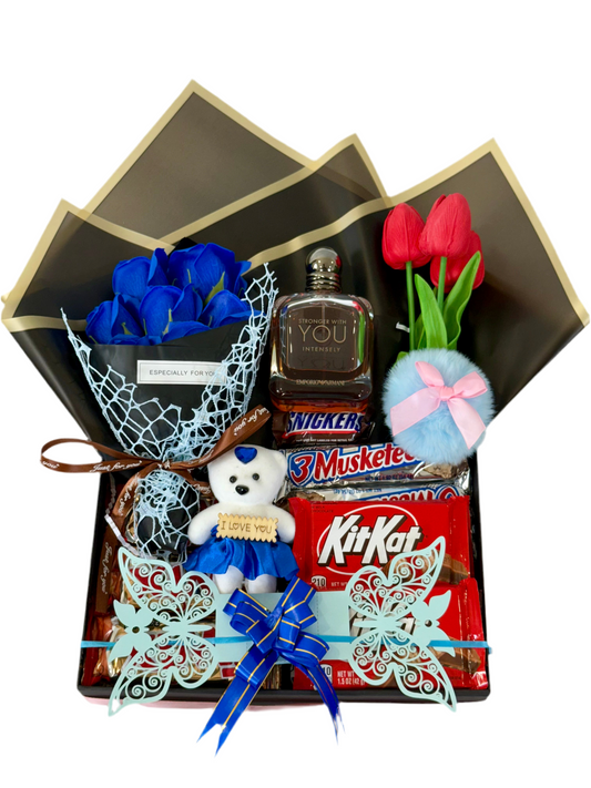 Gift basket with blue roses, red tulips, a bottle of alcohol, a teddy bear, and candy bars.