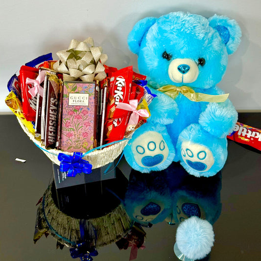 Blue teddy bear with a basket of chocolates on a reflective surface