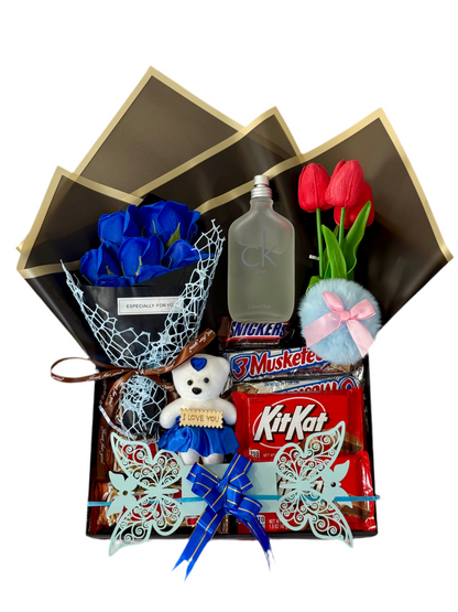 Gift box with blue roses, teddy bear, KitKat, and other items on a white background