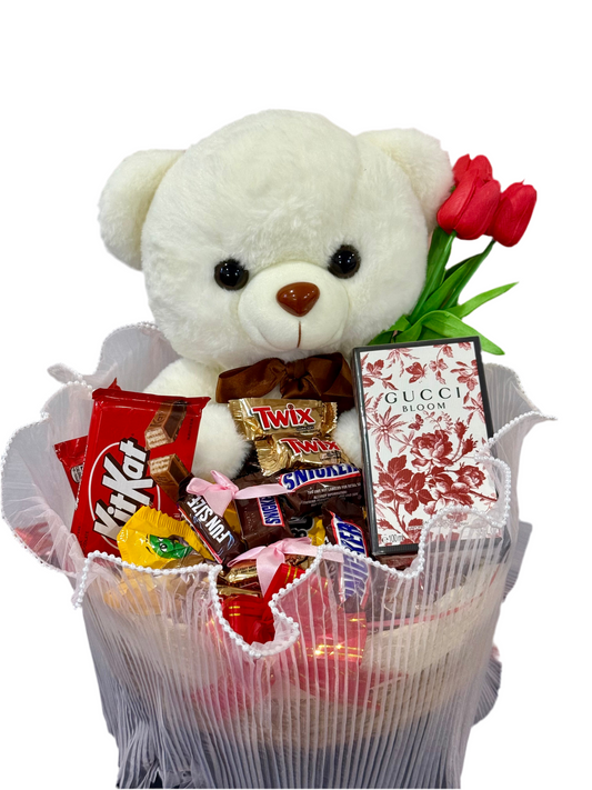 White teddy bear with a bouquet of flowers and candy in a decorative container on a white background